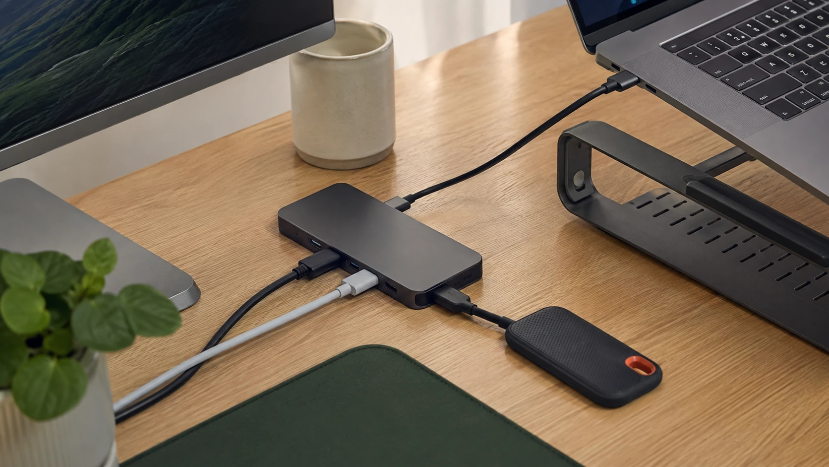 노트북 거치대 옆에 USB-C 허브와 케이블, 외장 SSD를 정리한 책상